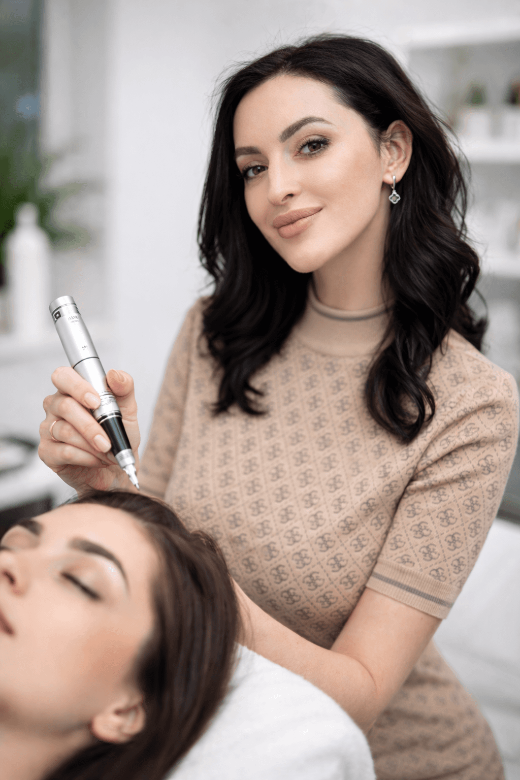 Professional beautician performing a permanent makeup procedure on a client's forehead in a studio.