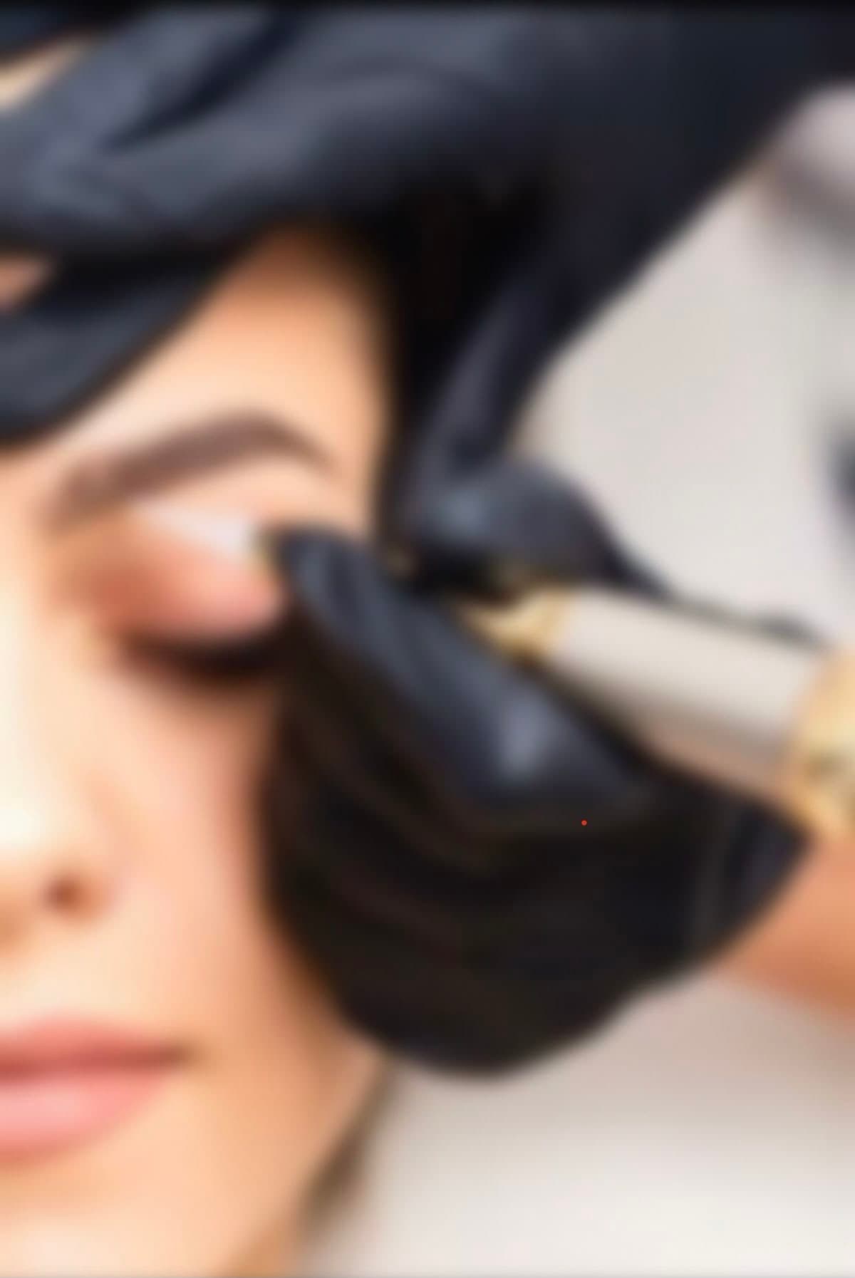 Technician in black gloves performing a permanent makeup procedure on a woman's eyelid.